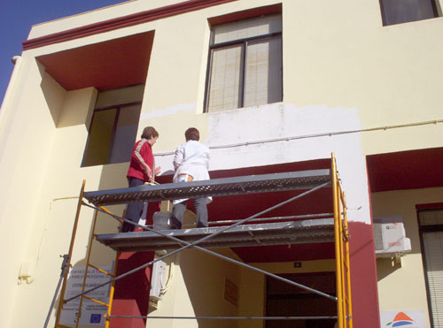 Alumnos/as del taller de pintura pintando el edificio de la Universidad Popular de Esparragosa de Lares, haga clic para ampliar la imagen